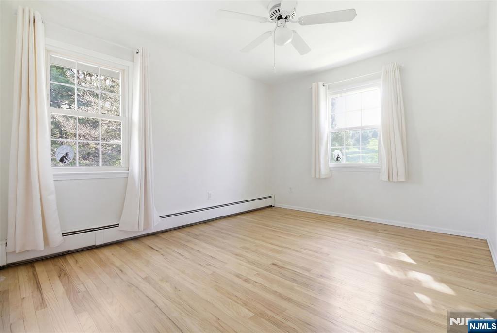 120 Carlough Road Upper Saddle River, NJ 07458 - Photo 15 of 25 an empty room with wooden floor fan and windows