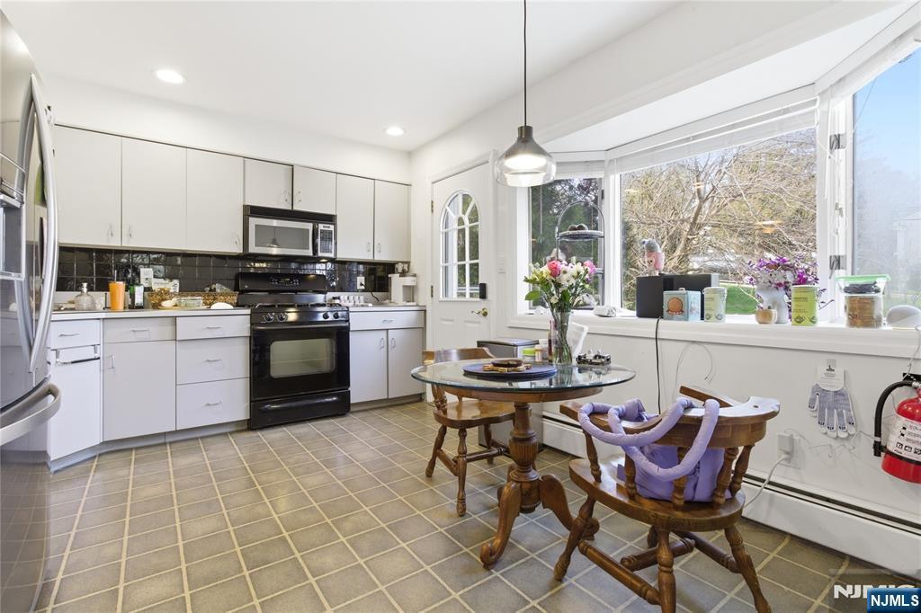 120 Carlough Road Upper Saddle River, NJ 07458 - Photo 7 of 25 a kitchen with stainless steel appliances a stove a sink a dining table and chairs