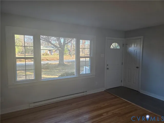 a view of an empty room with wooden floor and a window