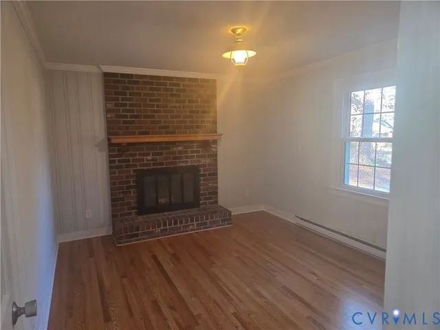 an empty room with wooden floor fireplace and windows