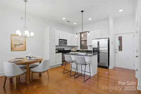 a kitchen with stainless steel appliances kitchen island a table and chairs in it