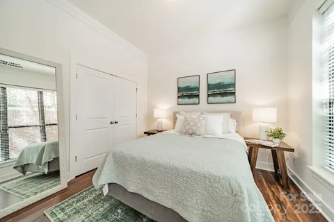 a bedroom with a bed a large window with wooden floor