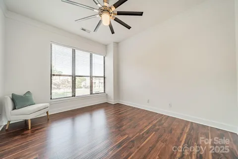 an empty room with wooden floor fan and windows