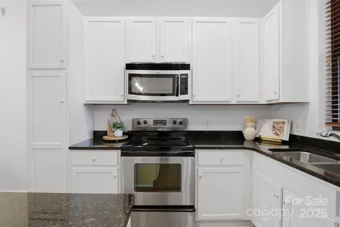 a kitchen with granite countertop white cabinets and stainless steel appliances