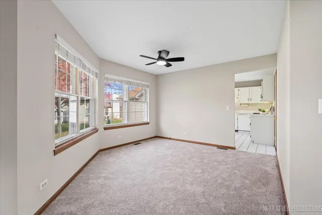 an empty room with chandelier fan and windows