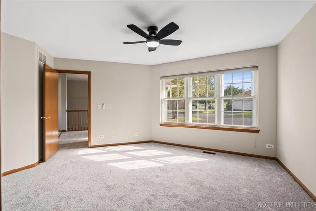 an empty room with ceiling fan and windows