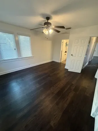 a view of an empty room with wooden floor and a window