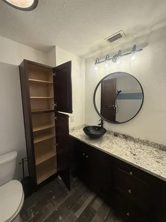 a bathroom with a granite countertop sink a toilet and a mirror