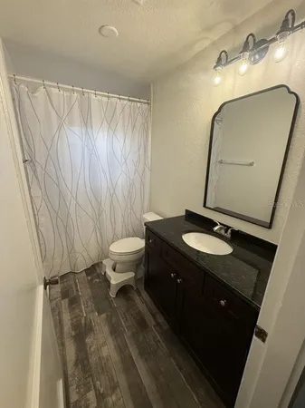 a bathroom with a sink vanity granite and toilet