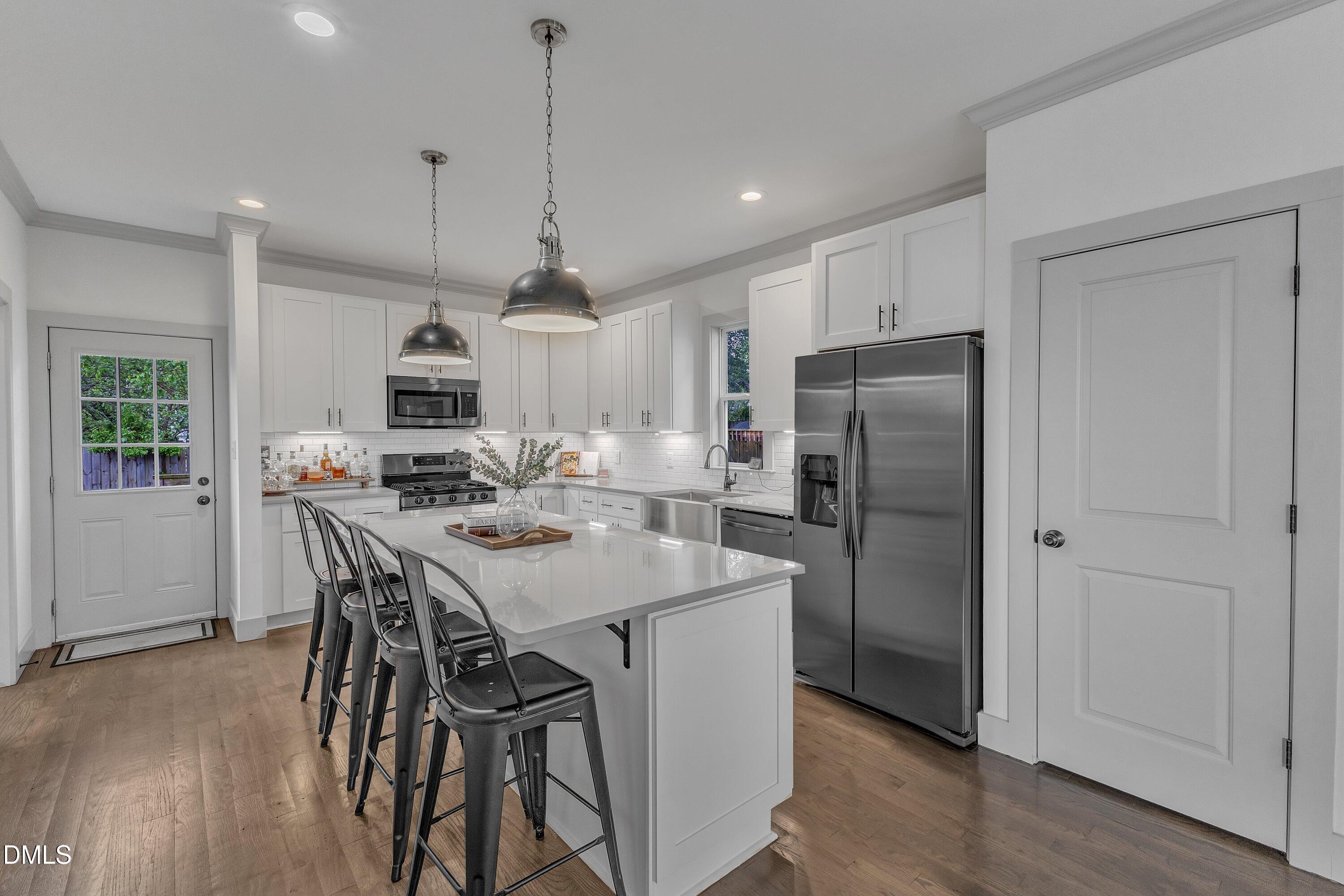 3 Maple Street Raleigh, NC 27610 - Photo 14 of 39 a kitchen with kitchen island a refrigerator a stove a sink a dining table and chairs with wooden floor