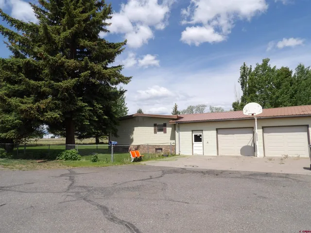 a view of a white house with a yard and plants
