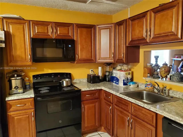 a kitchen with granite countertop a sink stove and cabinets