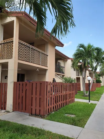 a view of a house with a small yard and wooden fence
