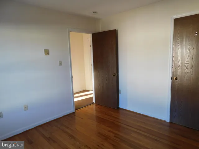 a view of an empty room with wooden floor and closet