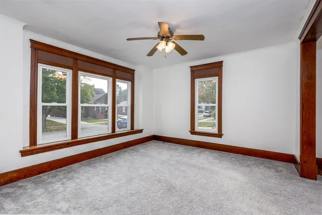 an empty room with windows and ceiling fan