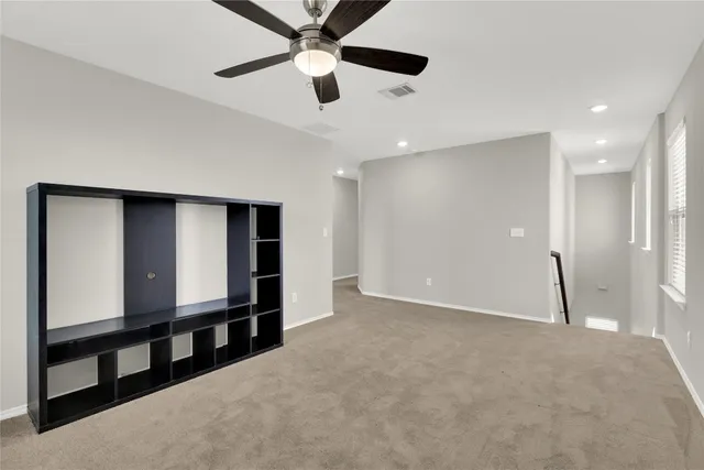 an empty room with windows and fan