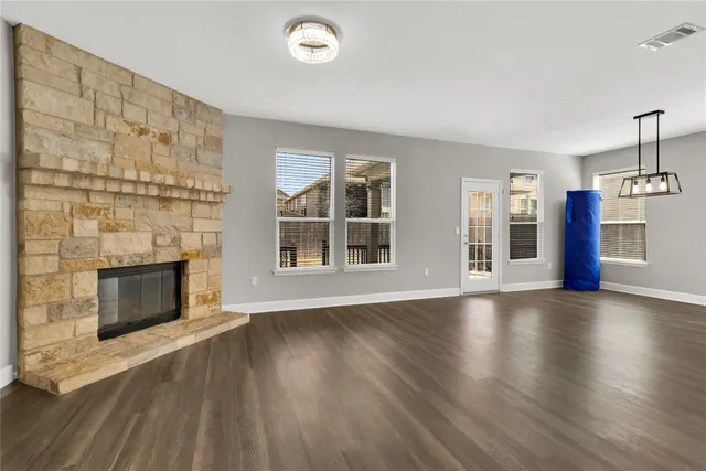 an empty room with wooden floor fireplace and windows