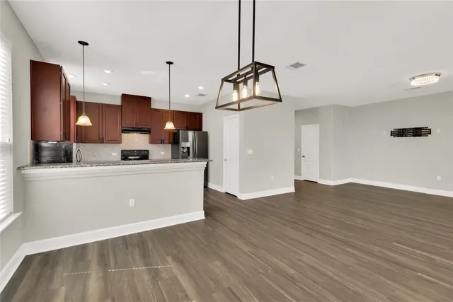 a view of kitchen with stainless steel appliances granite countertop cabinets and wooden floor