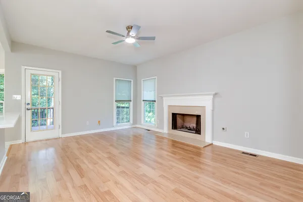a view of an empty room with a window and kitchen view
