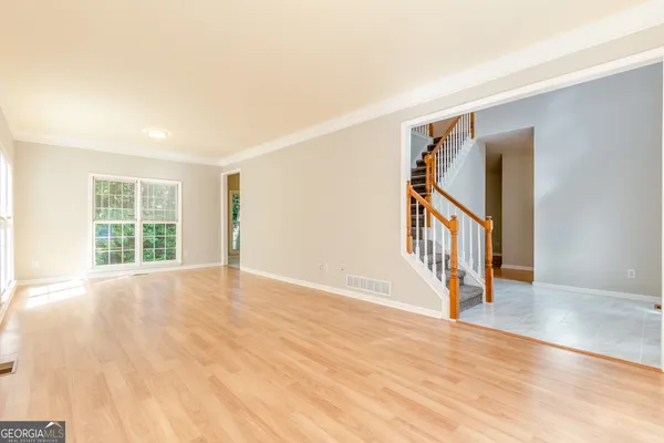 a view of an empty room with wooden floor and a window