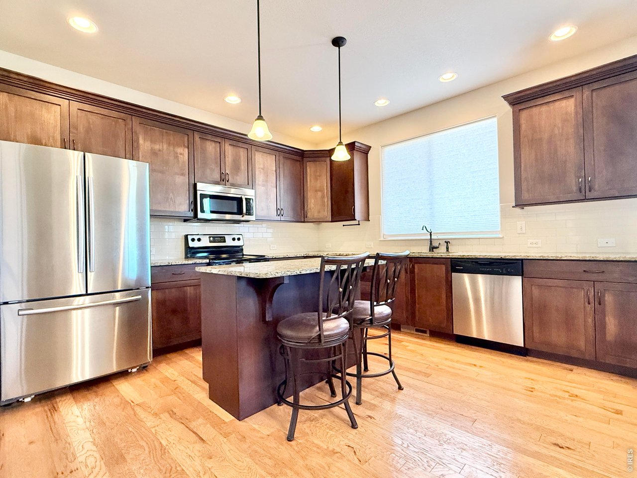 1215 5th Street Pierce, CO 80650 - Photo 4 of 22 a kitchen with stainless steel appliances granite countertop a refrigerator a stove top oven a sink dishwasher and a refrigerator with wooden floor