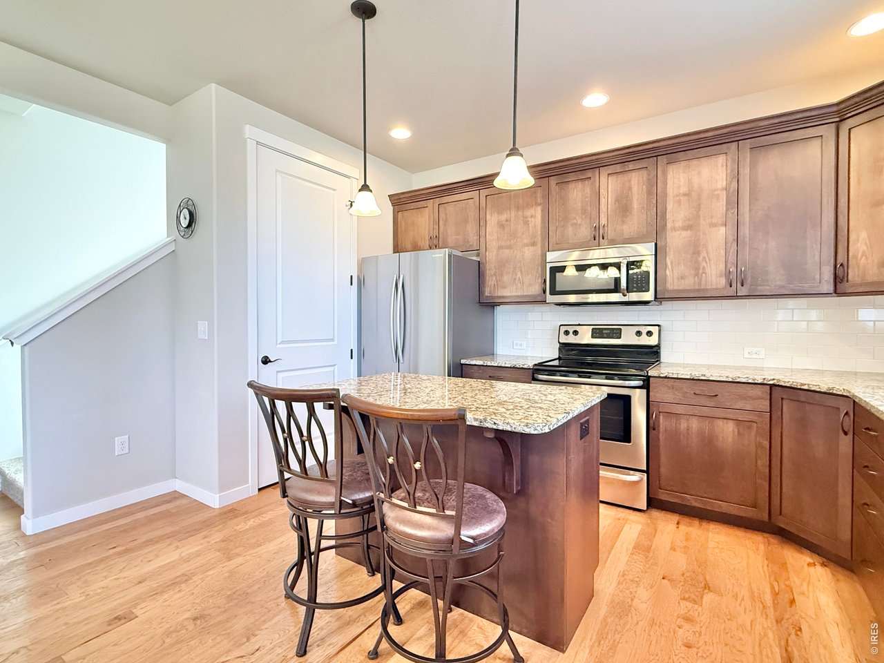 1215 5th Street Pierce, CO 80650 - Photo 5 of 22 a kitchen with stainless steel appliances granite countertop a kitchen island hardwood floor sink stove dining table and chairs