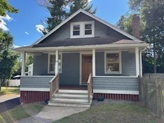 a view of a house with a yard and large tree