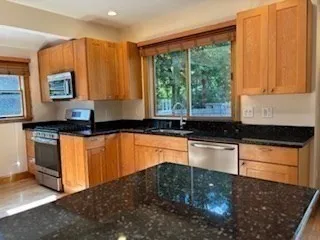 a kitchen with granite countertop a stove a sink and a microwave