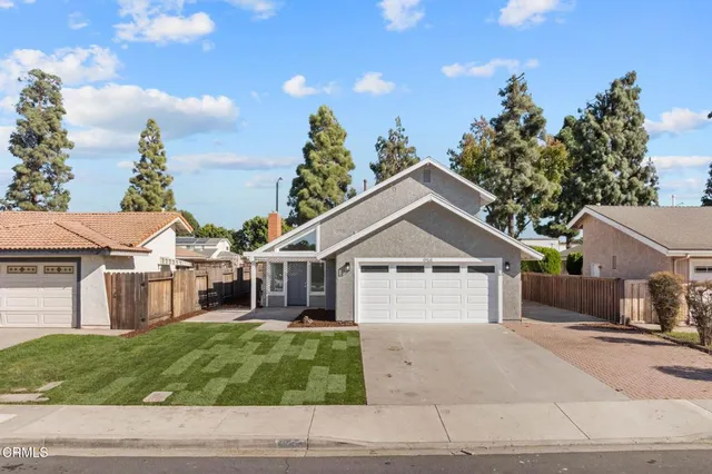 a view of a yard in front of a house with large windows