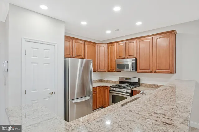 a kitchen with granite countertop a refrigerator and a stove top oven
