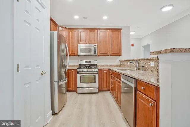 a kitchen with stainless steel appliances granite countertop a refrigerator sink and stove