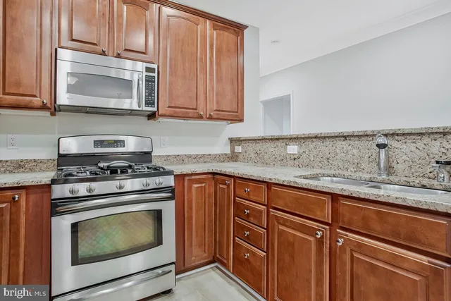 a kitchen with granite countertop cabinets stainless steel appliances and a sink