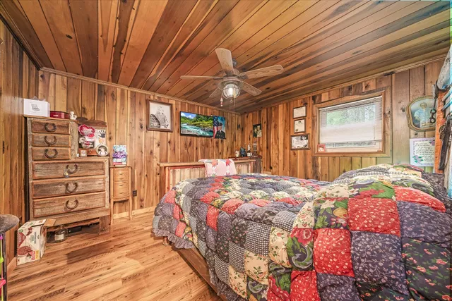 a bedroom with a bed a dresser and a large window