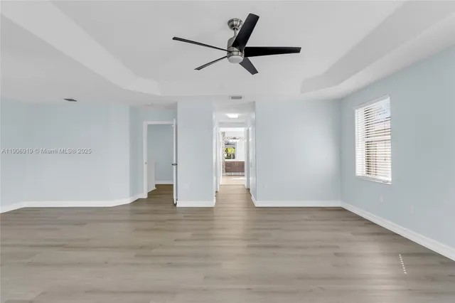 a view of empty room with wooden floor and ceiling fan