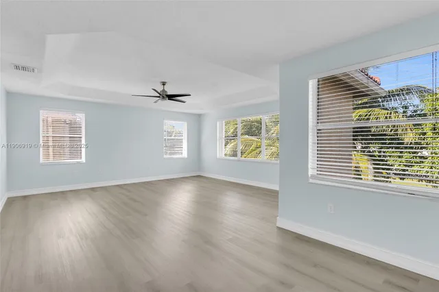 a view of an empty room with a window and wooden floor