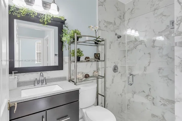a bathroom with a granite countertop sink toilet a mirror and shower
