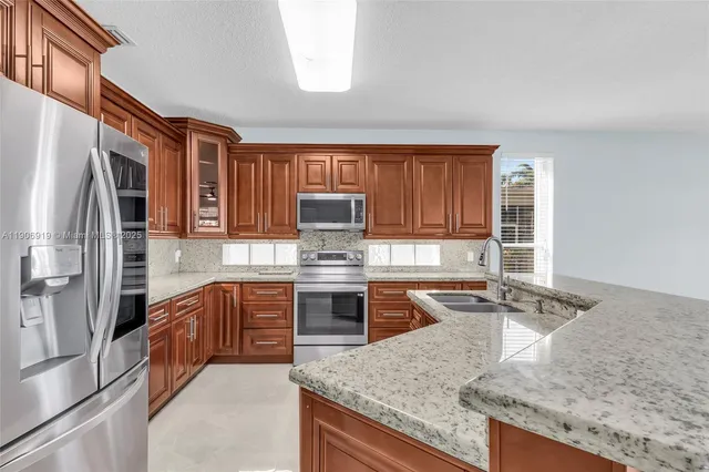 a kitchen with stainless steel appliances granite countertop a sink stove and refrigerator