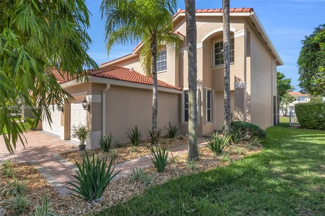 a backyard of a house with potted plants and palm trees
