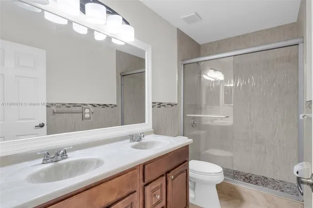 a bathroom with a sink a toilet a mirror and shower