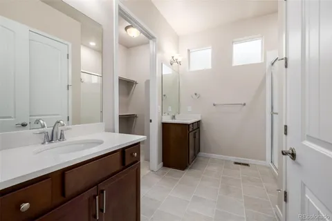 a spacious bathroom with a double vanity sink a mirror and a shower