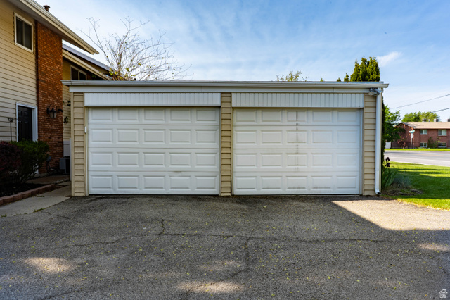 728 400 East Orem, UT 84097 - Photo 6 of 30 Two-car garage featuring individual panel doors, light-colored siding, and a paved driveway