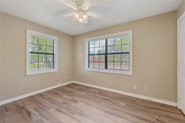 a view of empty room with wooden floor and fan