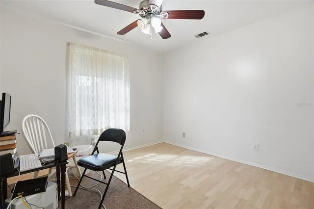 a view of a workspace with wooden floor and a ceiling fan