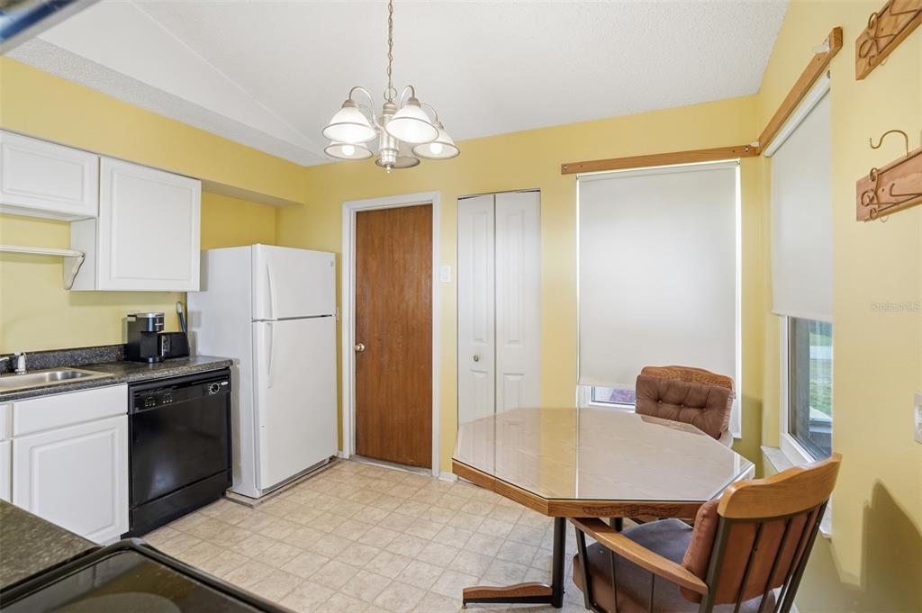 3280 Ambassador Avenue Spring Hill, FL 34609 - Photo 9 of 36 a kitchen with stainless steel appliances granite countertop a refrigerator a stove a sink dishwasher with a dining table and chairs