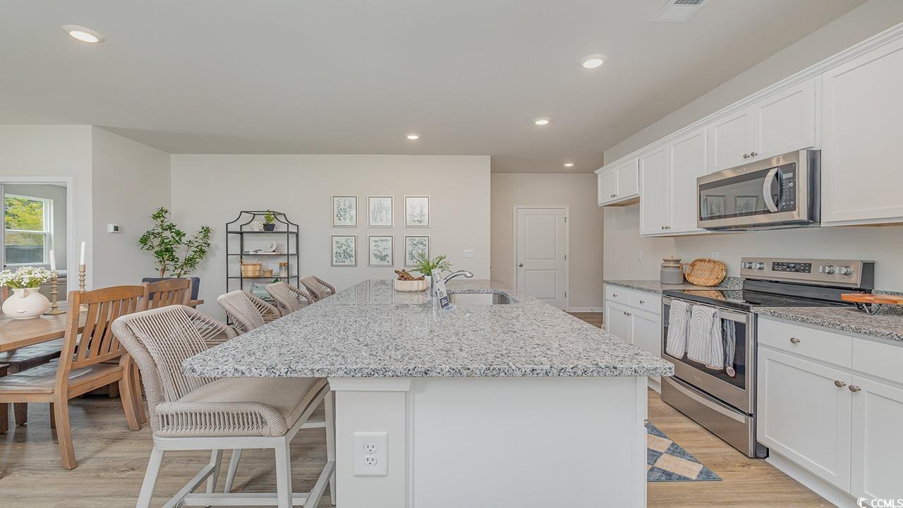 303 Ridley Street Longs, SC 29568 - Photo 5 of 31 Kitchen with a breakfast bar area, appliances with stainless steel finishes, light stone countertops, white cabinetry, and recessed lighting