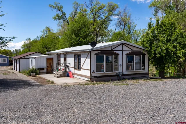 a view of a house with a yard and large tree