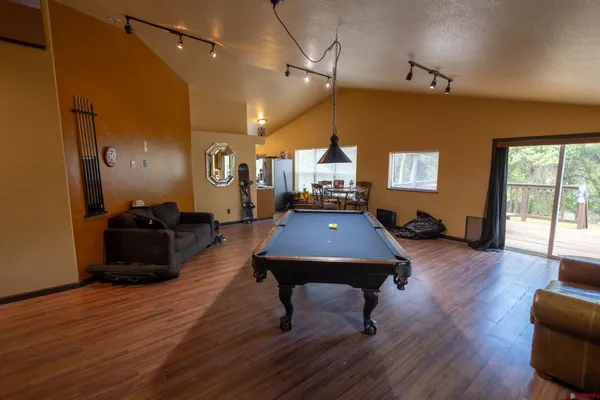 a room with furniture pool table wooden floor and windows