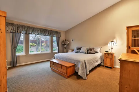 a bed sitting in a spacious bedroom next to a window