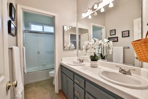 a bathroom with double vanity sinks a toilet a mirror and shower
