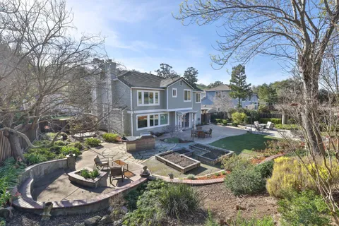 a front view of a house with a garden and lake view
